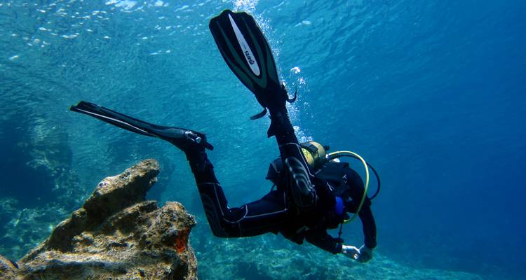 Scuba diver exploring an underwater rock formation.