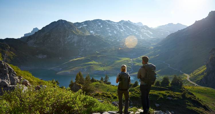 Zwei Personen stehen auf einem felsigen Aussichtspunkt mit einem malerischen Bergblick.