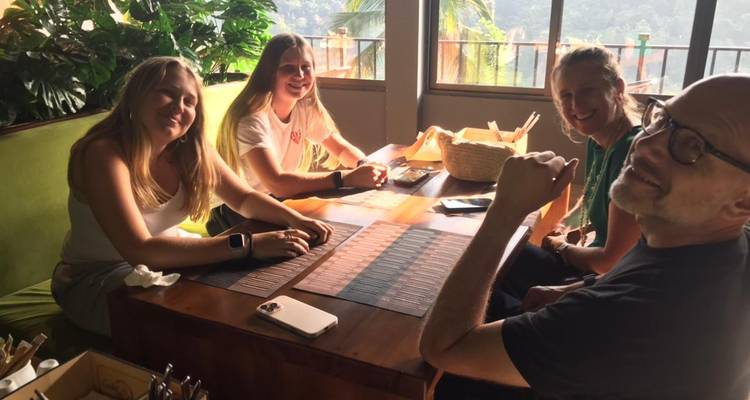 Groupe de personnes dînant à l'intérieur à une table avec vue sur l'extérieur.