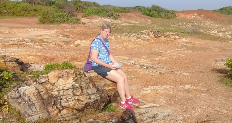 Femme assise sur un rocher dans une zone de paysage rocheux.