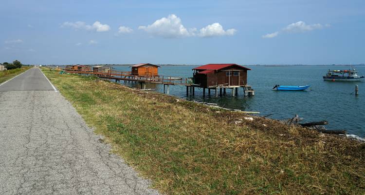 Vue panoramique de huttes en bois sur un plan d'eau, route le long du côté.