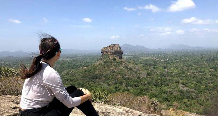 Personne assise sur un rocher avec vue sur le Rocher de Sigiriya en arrière-plan.