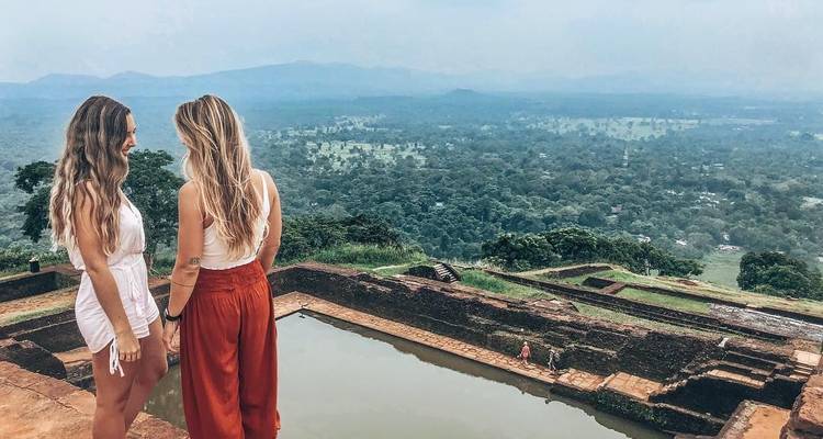 Deux personnes debout sur une plateforme avec vue sur la verdure et les bassins en contrebas.