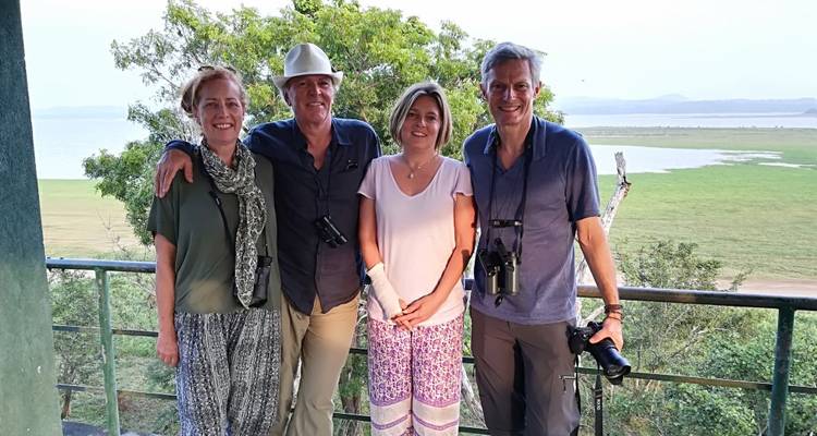 Quatre personnes posant sur un balcon avec des balustrades donnant sur un paysage.