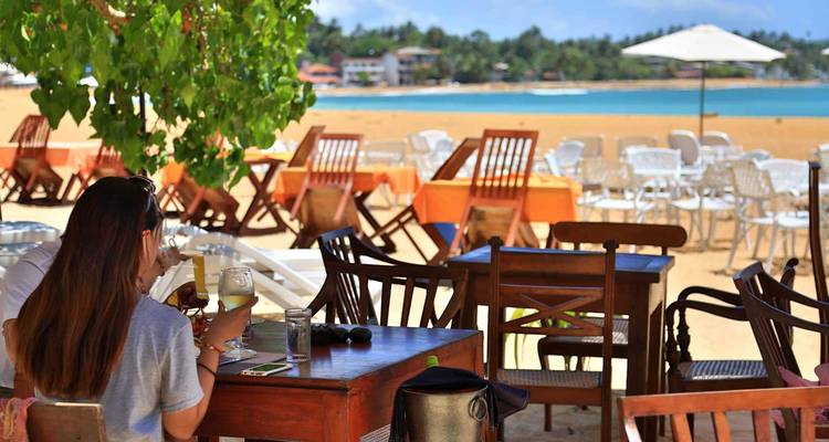 Des personnes dînent dans un restaurant en bord de mer avec une vue dégagée sur l'océan.