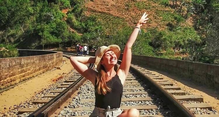 Femme assise sur des rails de chemin de fer, profitant du soleil.