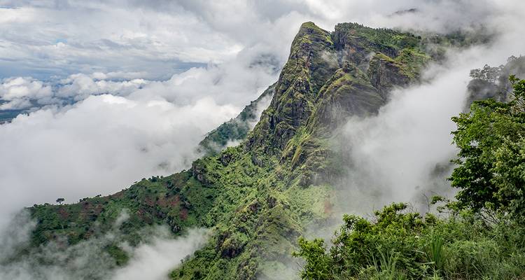 Mountain landscape with lush greenery and clouds.