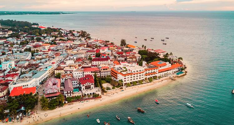 Aerial view of a coastal town with colorful buildings alongside a beach.