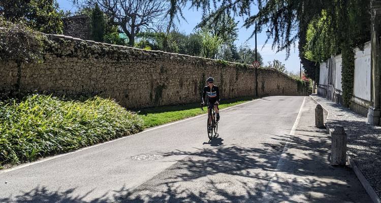 Cycliste roulant le long d'une route bordée de murs en pierre.