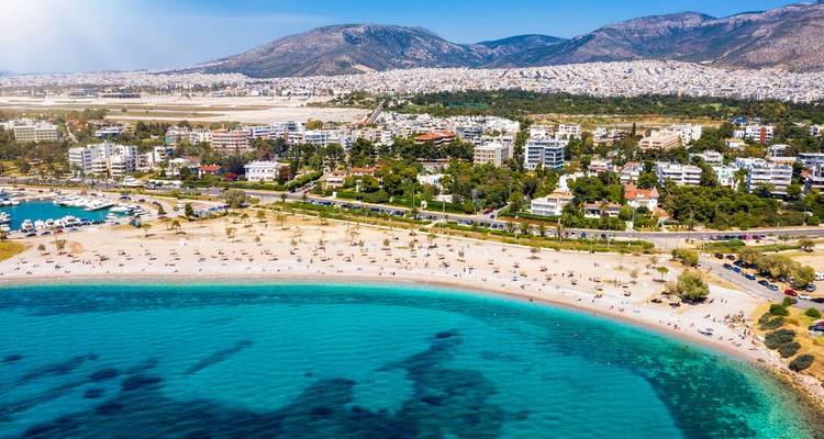 Aerial view of a beach with turquoise waters and city in the background.