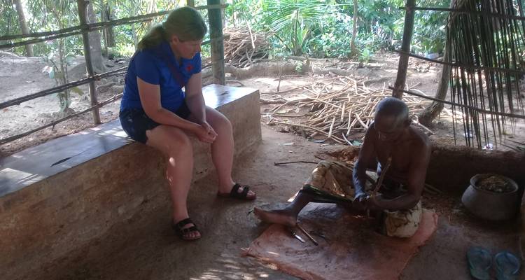 Personne assise avec un habitant local participant à une activité culturelle.