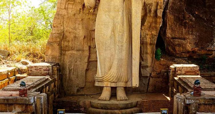 Une grande statue antique debout sculptée dans la roche.