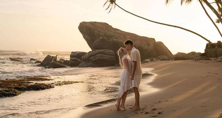 Couple debout sur une plage pendant le coucher du soleil.
