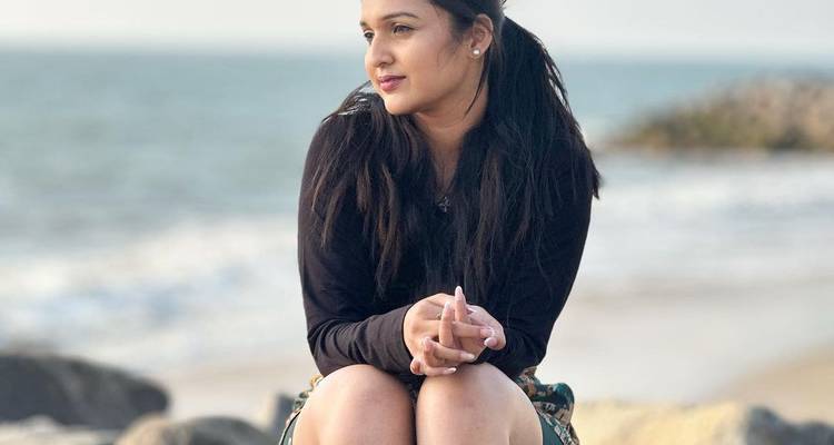 Femme assise sur les rochers au bord de la côte.