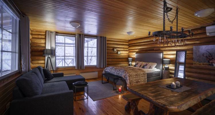 Cozy cabin interior with wooden walls and fur throws on the bed.