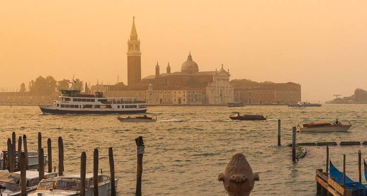 Venise avec des bateaux sur le canal au coucher du soleil.