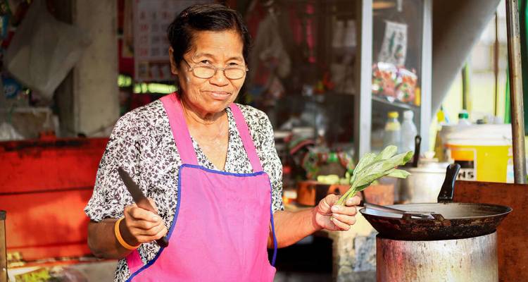 Femme préparant de la nourriture dans un stand de rue