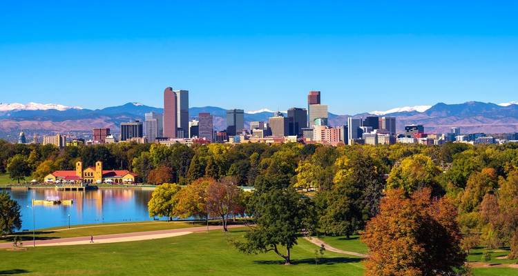 Cityscape of downtown Denver with a clear sky and mountainous backdrop.