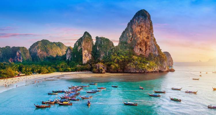 Des dizaines de bateaux à longue queue dans une baie vibrante entourée de falaises calcaires.
