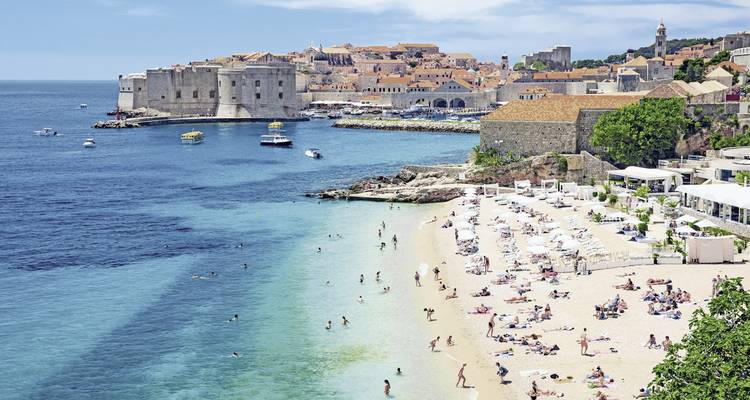 Plage populaire avec des gens qui se détendent et vue sur la ville.