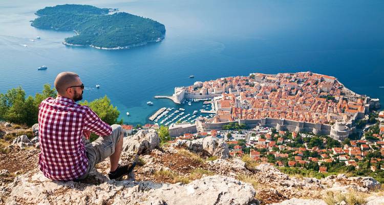 Personne assise sur une colline surplombant Dubrovnik et la mer.