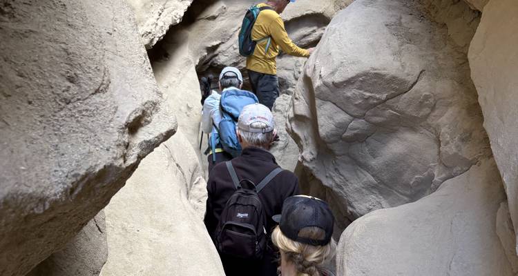 People walking through a narrow rocky passageway.