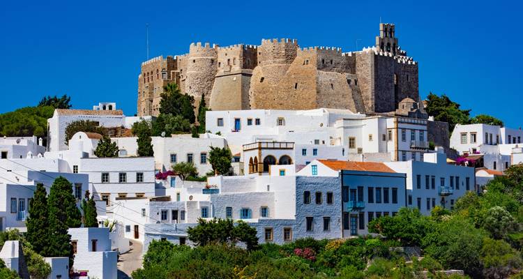 Structure semblable à un château entourée de bâtiments blancs sur une colline.