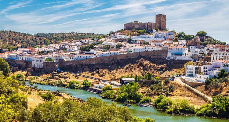 Whitewashed village on a hill with a river in front.