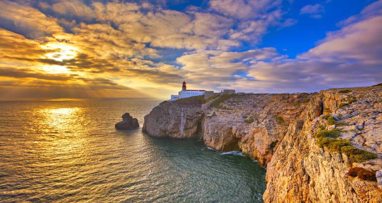 Dramatic sunset over a lighthouse on the cliffs.