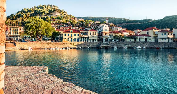 Seaside town with colorful buildings and hills in the background.