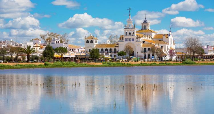 Una iglesia reflejándose en un lago bajo un cielo azul.
