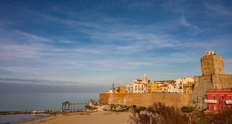 Kustlandschap met historische gebouwen en een vuurtoren aan zee.