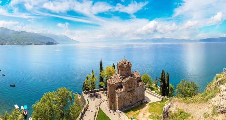 Église historique surplombant un vaste lac bleu.