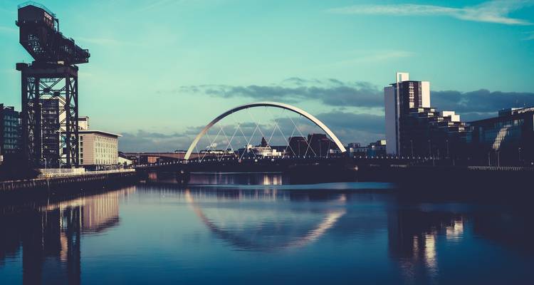 Pont moderne et bâtiments au-dessus d'une rivière calme à Glasgow.