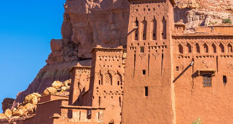 Ancien bâtiment de kasbah contre un arrière-plan rocheux avec un ciel bleu clair.