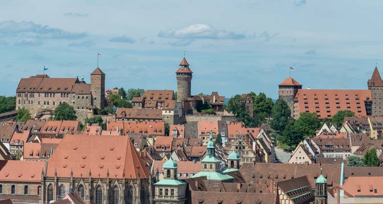 Vue du sommet d'une colline d'un château historique aux toits rouges.