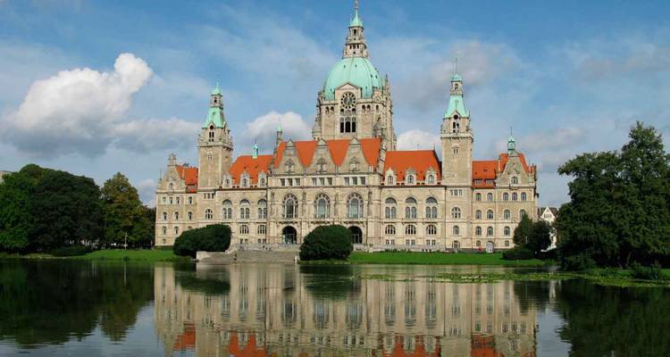 A grand neoclassical building with domes and spires overlooking a reflective pond.