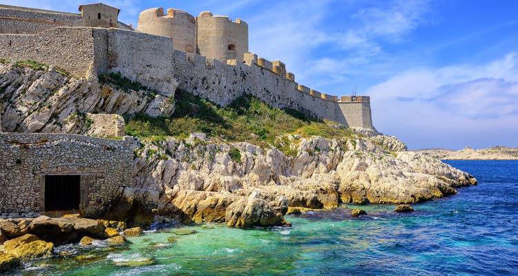 Une forteresse côtière isolée sur des îles rocheuses entourée d'eau bleue.