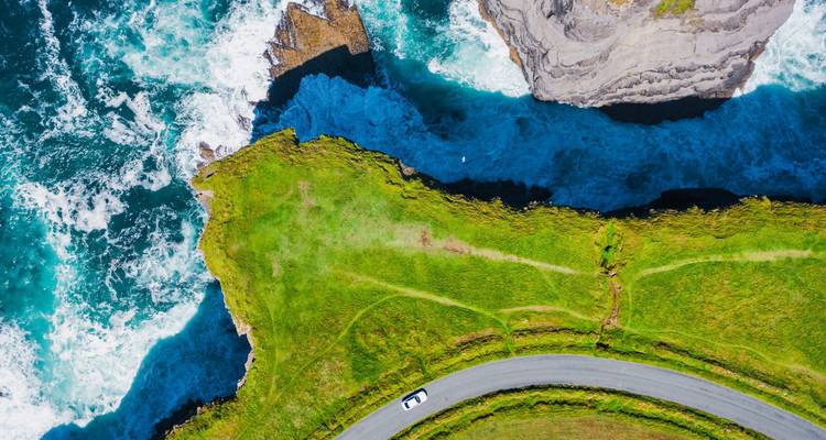 Vue aérienne d'une route de falaise surplombant un océan bleu clair.