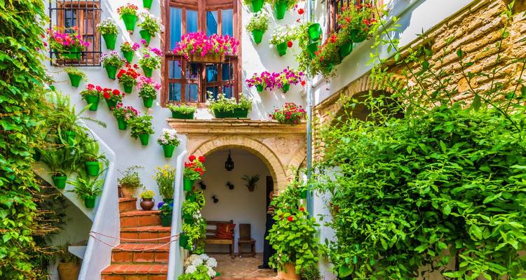Een pittoreske binnenplaats met kleurrijke bloemen en traditionele Spaanse architectuur.