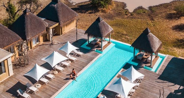 Resort-style pool with sun loungers and shaded areas.