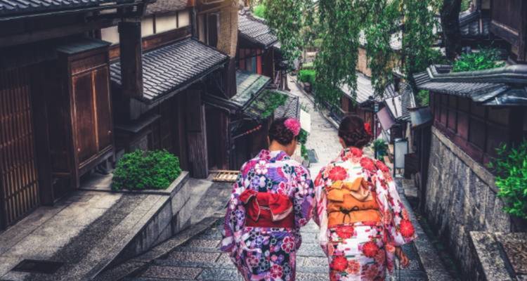 Deux personnes en kimonos traditionnels marchant dans une rue étroite.