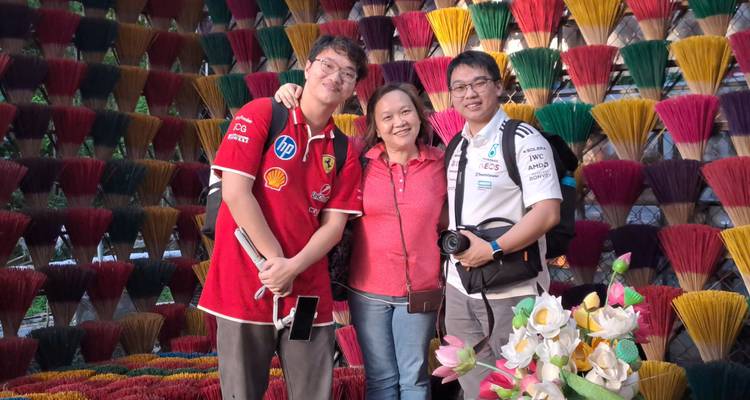 Trois personnes posant devant des bâtons d'encens colorés.