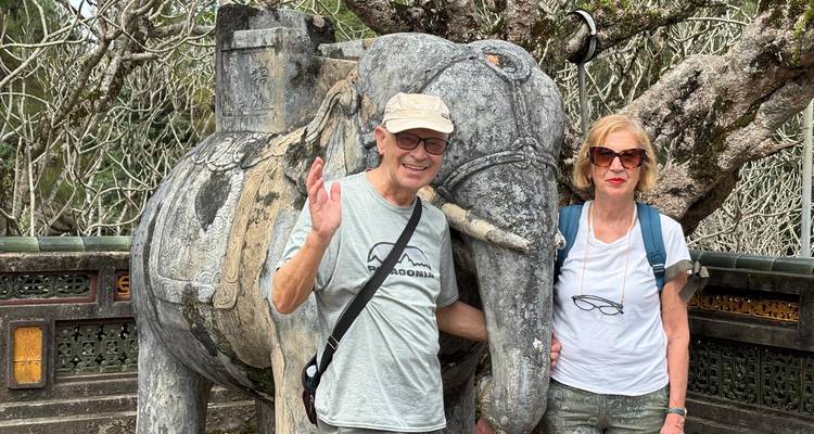 Couple se tenant debout à côté d'une statue d'éléphant en pierre.