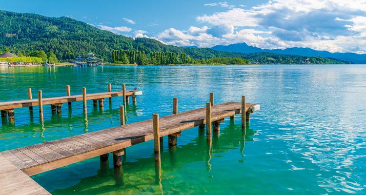Houten steigers die uitsteken in een turkooise meer omringd door bergen.