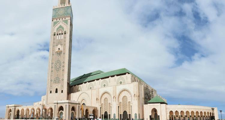 Le minaret imposant et les arches de la mosquée Hassan II s'élèvent sous un ciel lumineux.