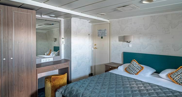 Intérieur d'une chambre de cabine avec un lit et un miroir.