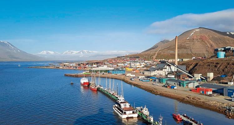 Ville côtière du Svalbard avec des bâtiments colorés et des bateaux amarrés.