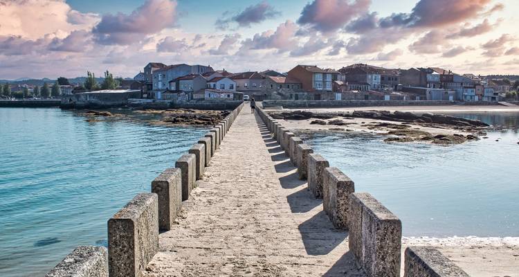 Brücke, die bei Sonnenuntergang in ein Küstendorf führt.