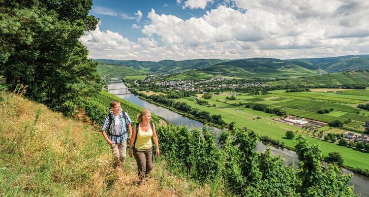 Couple faisant de la randonnée le long d'une colline surplombant une rivière dans un cadre champêtre pittoresque.